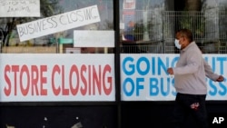 Čovjek prolazi pored izloga prodavnice u Ilinoisu, koja ne radi zbog COVID-19 (Foto: AP)