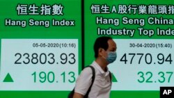 A man wearing face mask walks past a bank electronic board showing the Hong Kong share index Tuesday, May 5, 2020.