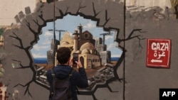 Seorang pria mengambil gambar grafiti yang mewakili rekonstruksi Gaza, di bagian tembok pemisah Israel, di Betlehem di Tepi Barat yang diduduki pada 12 Februari 2025. (Foto: Hazem Bader/AFP)