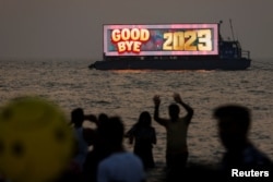 People watch the last sunset of the year from a beach on New Year's eve in Mumbai, India, Dec. 31, 2023.