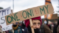 A woman holds a banner reading "They are us" as she takes part in demonstration initiated by Polish mothers in front of the border guard office in Micholowo, Poland, to protest the deportation of migrants to Belarus on October 23, 2021.