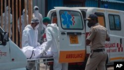 Petugas kesehatan membawa jenazah seseorang yang meninggal karena COVID-19 di luar rumah sakit lapangan di Mumbai, India, Selasa, 4 Mei 2021. (Foto: AP)