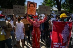 Protesters hold up signs as they take part in a demonstration against the military coup in front of the Chinese embassy in Yangon, Feb. 11, 2021.