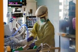 FILE - A health care worker tends to a COVID-19 patient in the intensive care unit at Santa Clara Valley Medical Center during the coronavirus pandemic in San Jose, California, January 13, 2021.