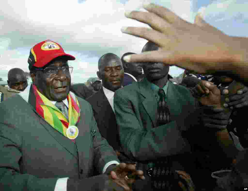 Le président Robert Mugabe, à gauche, salue la foule lors d&#39;un rassemblement à Gutu, à 220 kilomètres au sud de Harare, le 17 mars 2005.