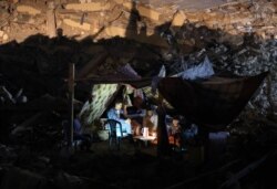 Warga Palestina duduk di tenda yang telah didirikan di atas reruntuhan bangunan yang hancur akibat serangan udara Israel baru-baru ini, di Kota Gaza, pada 24 Mei 2021. (Foto: AFP)