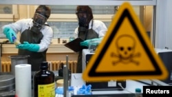 FILE - Employees of an OPCW-linked lab inspect dummy samples contaminated with a substance similar to Sarin during a demonstration in Muenster, Germany, Oct. 15, 2013.