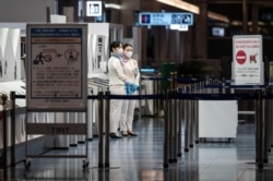 Anggota staf berdiri di gerbang keberangkatan bandara internasional Haneda Tokyo pada 29 November 2021, ketika Jepang mengumumkan rencana untuk melarang semua pelancong asing baru karena adanya varian omicron. (Foto: AFP)