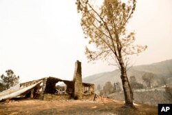 A burned structure stands atop a hill on Yaqui Gulch Road as a wildfire burns near Mariposa, Calif., July 19, 2017.