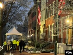 Палатка безопасности, через которую проходят пешеходы, идущих по тротуару возле Белого дома