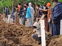 Relatives attend funerals of family members who died from the coronavirus at a cemetery for COVID-19 victims in TPU Rorotan, north Jakarta, Indonesia, July 8, 2021. (Indra Yoga/VOA Indonesian)