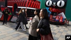Shoppers walk by a promotion by Alibaba's Tmall online shopping platform for the upcoming 10th Singles Day event in Beijing, China, Nov. 7, 2018. The holiday began in the '90s by Chinese college students as a version of Valentine's Day for people without romantic partners.