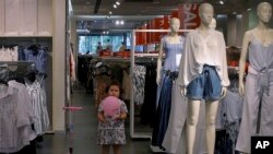 A child plays with a balloon at a clothing store having a promotion sale in Beijing, July 15, 2019. China's economic growth sank to its lowest level in at least 26 years.