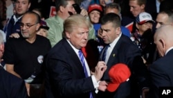 Republican presidential candidate Donald Trump signs a hat after a rally in Novi, Mich., Sept. 30, 2016.
