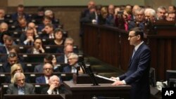 Poland's Prime Minister Mateusz Morawiecki, standing, vows to protect U.S. – EU ties and the crucial role of NATO, against criticism from some other European leaders, during his policy speech in Warsaw, Nov. 19, 2019.
