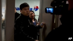 Petugas Malaysian Airlines berusaha menghindari pertanyaan dari wartawan di Bandara Internasional Beijing, China, Sabtu (8/3).