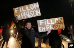 A demonstrator holds placards reading "Fillon in jail' ahead of the French conservative presidential candidate Francois Fillon's campaign rally in Compiegne, north of Paris, Feb. 15, 2017.
