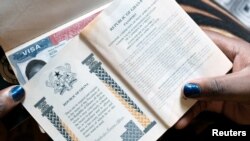 Žena iz Gane drži pasoše svoje porodice sa američkim vizama.