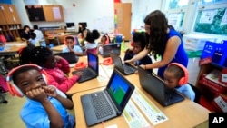 Second grade student Khalil Morgan, left, reacts after completing an interactive math problem on his computer, with teacher Jillian Martin, standing to the right, at Turner Elementary School in southeast Washington, Tuesday, Aug. 29, 2017. (AP Photo/Manue