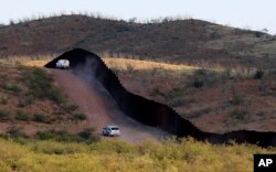 FILE - U.S. Border Patrol agents monitor the border fence in Naco, Ariz., Oct. 2, 2012. National Guard contingents in U.S. states that border Mexico say they are waiting for guidance from Washington to determine what they will do following President Donald Trump's April 4, 2018, proclamation directing deployment to fight illegal immigration and drug smuggling.