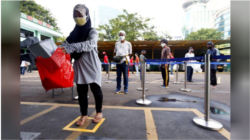 Warga Jakarta mengenakan masker saat antre untuk menerima pembagian beras saat pemberlakuan PSBB di DKI Jakarta.