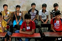 FILE - Young Indian bonded child laborers wait to be processed at a safe house after being rescued during a raid by workers from Bachpan Bachao Andolan, or Save the Childhood Movement, at a factory in New Delhi, India, June 11, 2013.