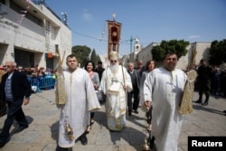 The head of the Greek Orthodox church in Bethlehem Bishop Theofilactos receives the 'Holy Fire' after its arrival from from Jerusalem's Holy Sepulchre, outside in the Church of the Nativity in the West Bank town of Bethlehem, April 15, 2017.