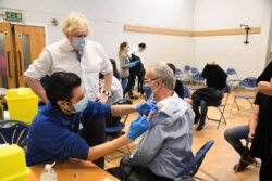 Perdana Menteri Inggris Boris Johnson mengunjungi pusat vaksinasi Stow Health di Westminster, London, Inggris, 13 Desember 2021. (Foto: Reuters)