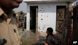 FILE - Indian security personnel inspect a house allegedly damaged by from gunfire from the Pakistan side of the border, at a residential area near the international border at Bidipur, in Ranbir Singh Pura, India, Oct. 22, 2016.