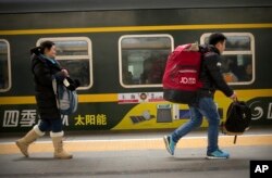Passengers run to board a train at the Beijing Railway Station in Beijing, Jan. 30, 2016.
