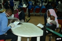 FILE - A Cameroonian police officer registers the arrival from Libya of a Cameroonian woman and her son at the Yaounde International Airport in Cameroon, Nov. 22, 2017.