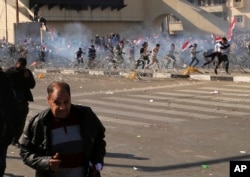 Protesters run from tear gas fired by security forces, during a demonstration by followers of Iraq's influential Shi'ite cleric Muqtada al-Sadr, in Baghdad, Iraq, Feb. 11, 2017.