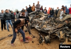 Palestinians inspect the remains of a vehicle that was destroyed in an Israeli air strike, in Khan Younis in the southern Gaza Strip, Nov. 12, 2018.