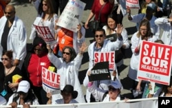 FILE - Health care professionals join hundreds of people marching through downtown Los Angeles protesting President Donald Trump's plan to dismantle the Affordable Care Act, his predecessor's signature health care law, March 23, 2017.
