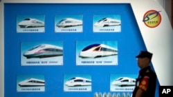 FILE - A security official stands near a display showing different models of Chinese trains at a maintenance yard during a media tour ahead of the 2018 Forum on China-Africa Cooperation in Beijing, Aug. 30, 2018. This year's forum is set for Sept. 5-6. 