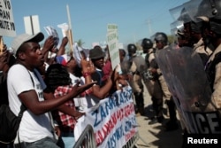 A supporter of Haitian Senator-elect Guy Philippe, who was arrested and extradited to the U.S., speaks to a police officer during a protest in front of the U.S. embassy in Port-au-Prince, Jan. 13, 2017.