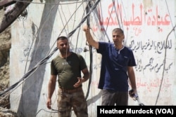 Hazzam Abdulghani holds up prayer beads he finds on the body, cursing IS and saying he knows now it is his nephew in Mosul, Iraq, June 15, 2017.