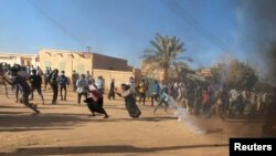FILE - Sudanese demonstrators run from a teargas canister fired by riot policemen to disperse them as they participate in anti-government protests in Omdurman and Khartoum, Sudan, Jan. 20, 2019.