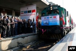 FILE - Iranian officials applaud on the platform as the first train connecting China and Iran arrives at Tehran Railway Station, Feb. 15, 2016.