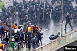 A member of the riot security forces (R) points what appears to be a pistol towards a crowd of demonstrators during a rally against Venezuela’s President Nicolas Maduro’s government in Caracas, June 19, 2017.