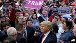 FILE - Republican presidential candidate Donald Trump holds up a sign handed to him by a supporter after speaking at a campaign rally in Bethpage, New York, April 6, 2016. Trump insist that he "always buys the rights" for songs played at his rallies.