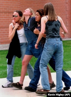 In this Tuesday, April 20, 1999 file photo, four unidentified young women head to a library near Columbine High School where students and faculty members were evacuated after two student gunmen went on a shooting rampage in the school near Denver.