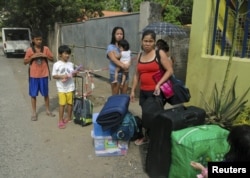 FILE - Residents wait for a truck to transport them into an evacuation center as local officials ordered enforced evacuation ahead of Typhoon Bopha in Cagayan de Oro City, southern Philippines, December 3, 2012.