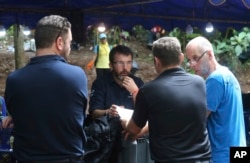 Australian Federal Police and Defense Force personnel talk each other near a cave where 12 boys and their soccer coach are trapped, in Mae Sai, Chiang Rai province, in northern Thailand, July 5, 2018.