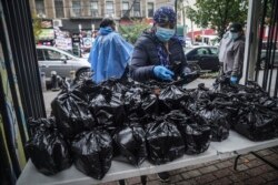 Volunteer Dolly Caulderon, center, prepares to hand out boxed meals prepared at the South Bronx restaurant La Morada, Wednesday Oct. 28, 2020, in New York.