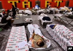 Evacuees from a wildfire rest on cots and blanket supplied by the Red Cross in the gymnasium at Taft Charter High School in the Woodland Hills section of Los Angeles on Nov. 9, 2018.