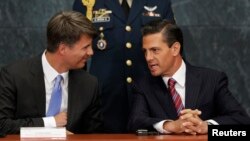 FILE - Mexico's President Enrique Pena Nieto, right, talks with BMW production chief Harald Krueger, left, during the announcement of the new BMW factory in Mexico, in Mexico City, July 3, 2014.