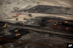 FILE - Vehicles work at an open-pit coal mine near Ordos in northern China's Inner Mongolia Autonomous Region.
