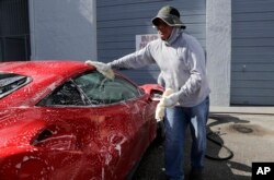 FILE - Jorge Tume washes a car in Miami, Florida, June 27, 2017.