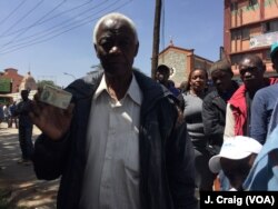 A potential voter shows his national ID card, as he waits in line at Nairobi's St. Peter Clavers primary school to register to vote, Jan. 16, 2017. (Photo: J. Craig / VOA)
